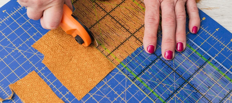 A imagem mostra um ambiente de oficina criativa e colaborativa, focado na produção artesanal de sacolas de tecido (ecobags)